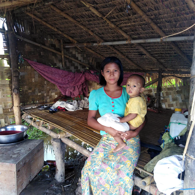 Single mother with child, posing inside their hut